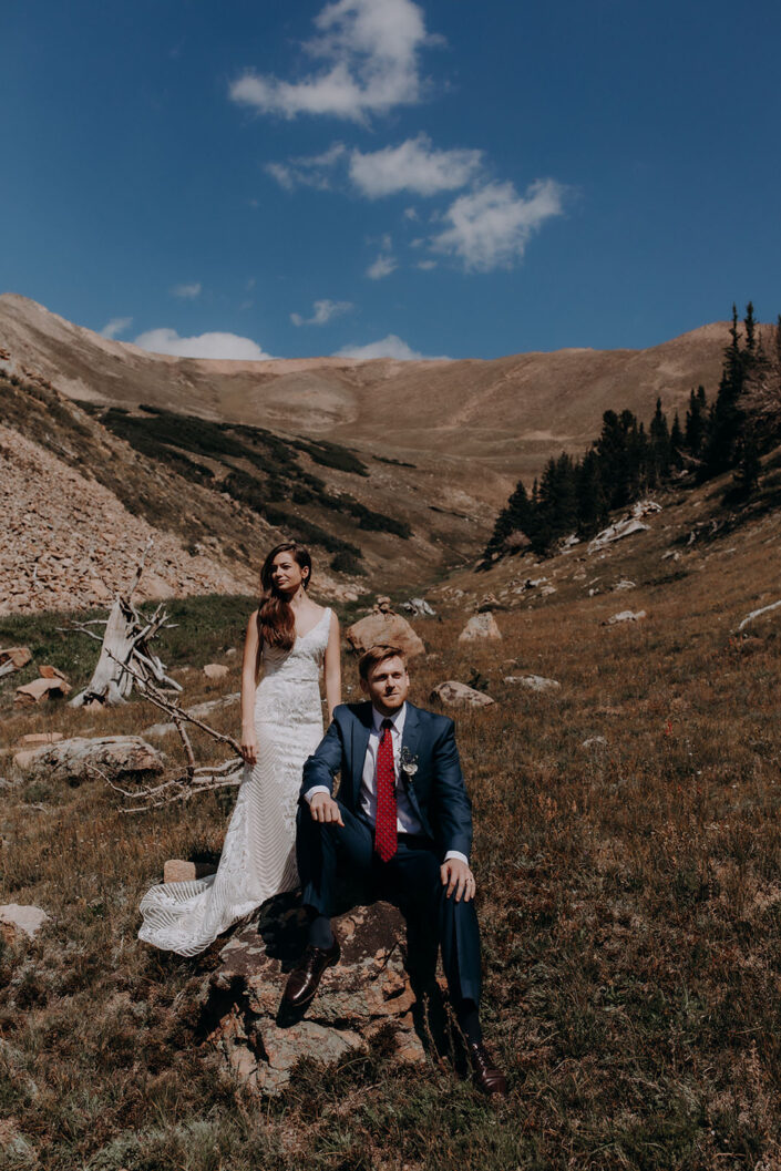 stoic pose of bride and groom in mountain field