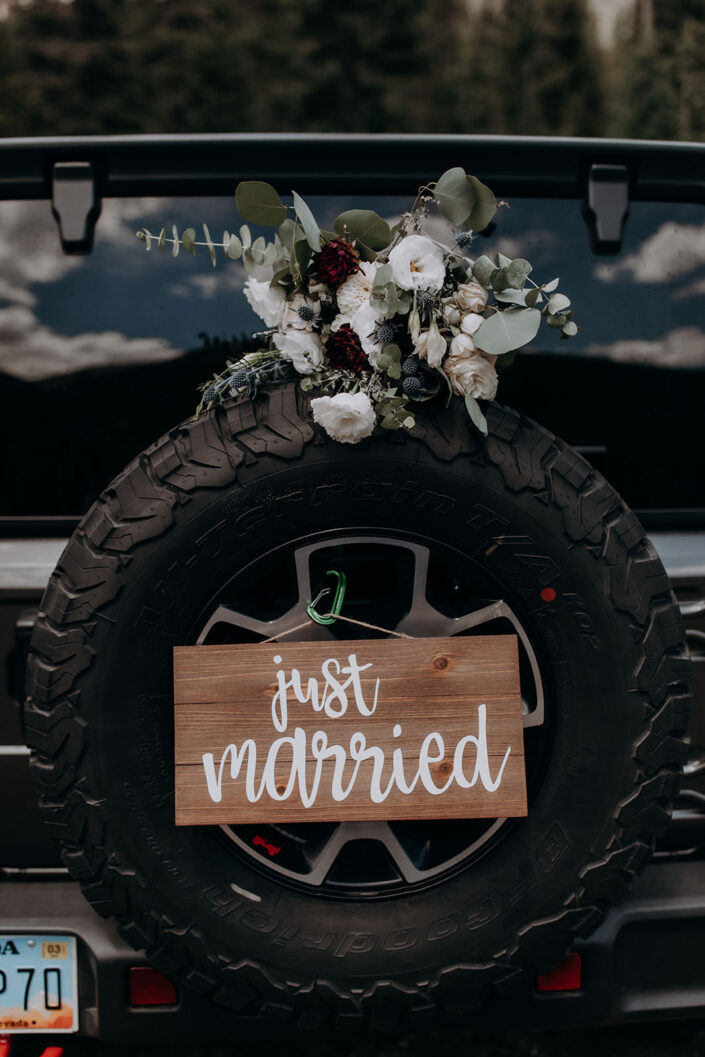 just married sign hanging from spare tire on jeep