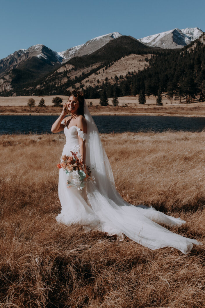 Full length portrait of bride laughing in front of mountains