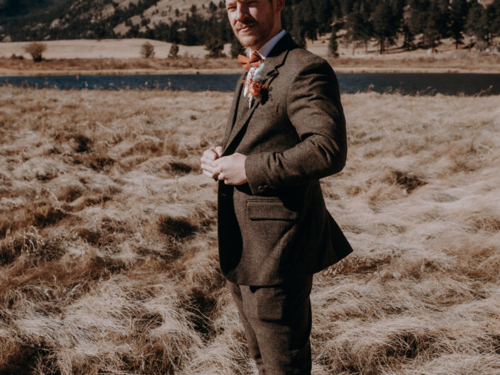 Full length portrait of groom button jacket with mountains in background