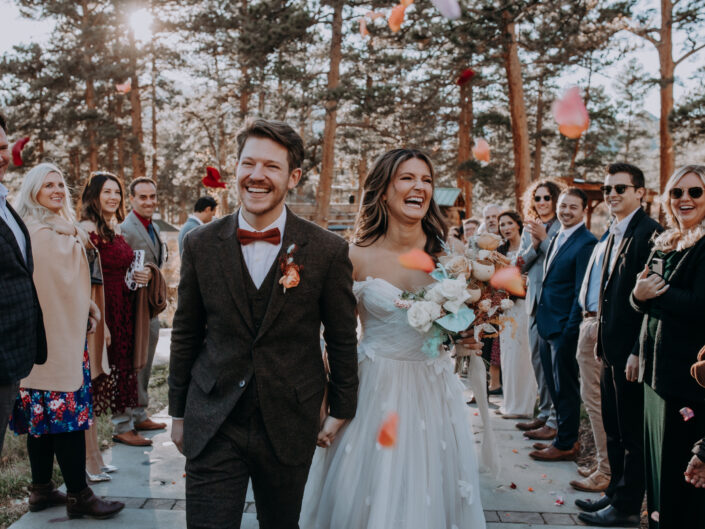 bride and groom laugh and walk while guests toss flowers