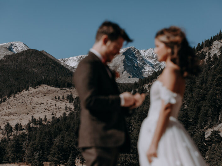 camera focuses on mountain between couples as groom reads his vows
