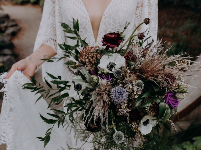 bride holding bouquet of purple and white flowers