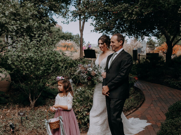 bride is escorted by her father and flower girl to ceremony